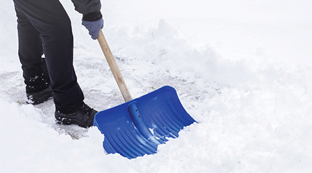 Close-up of person shoveling snow on a sidewalk