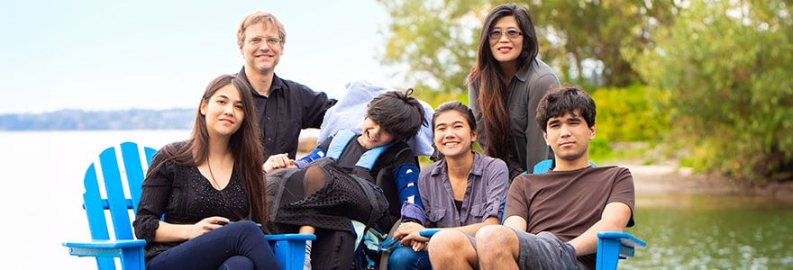 Family of six, one of them in a wheelchair, posing by a river