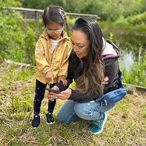 Parent and child in a local park looking at a mobile device