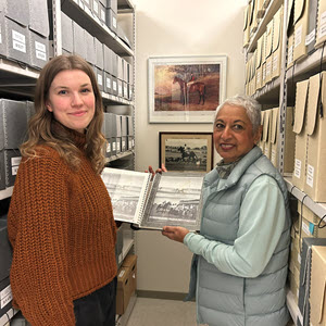 Two staff from archives displaying a book
