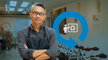 Bike shop owner with recycling logo behind him