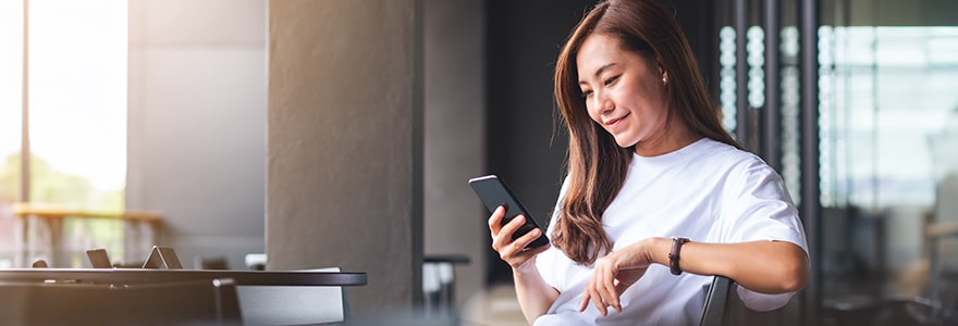 Young woman holding and using mobile phone