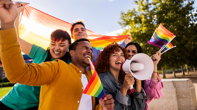 A diverse group of people with pride flags