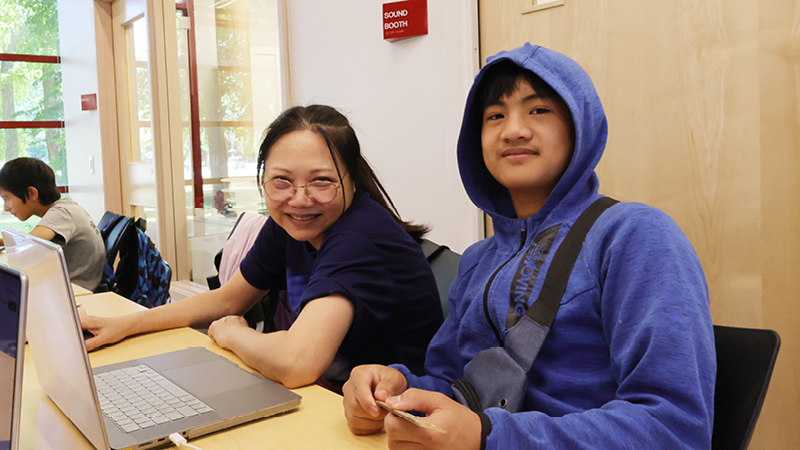 Two Youth sitting at a table with a laptop