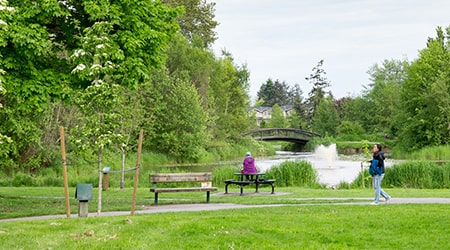 View of Garden City Park including the pond, bridge, park bench and trail