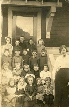 Black & White Photo of Young Students Sitting on Steps of School