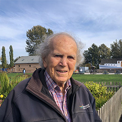 A man standing on a wooden walkway with heritage buildings in the background