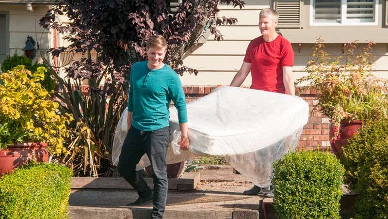 two men carrying a mattress