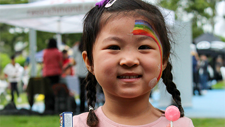 Close up of a little girl with rainbow face painting