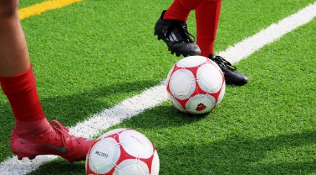 View of a soccer ball being kicked on a turf field