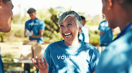 Smiling volunteer in conversation with others in a park setting