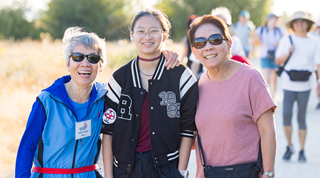 Three women on a sunny trail, participating in a walking club