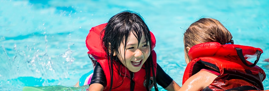 Two children wearing life jackets in an outdoor pool