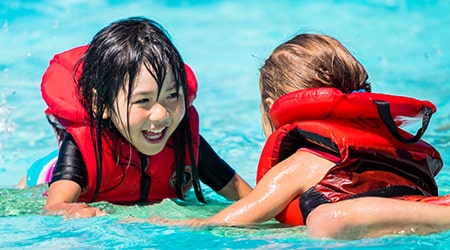 Two girls swimming in an outdoor pool