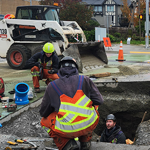 Utility crew working around a large excavation site with construction equipment