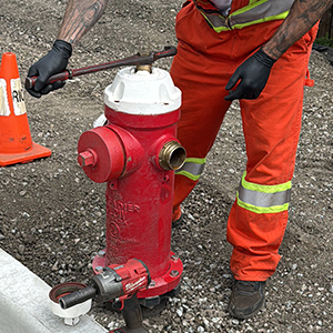 Worker conducting annual fire hydrant maintenance on a city street